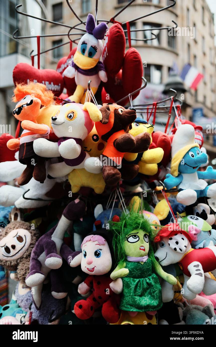 Giocattoli di peluche colorati appesi a una vetrina di strada a Belgrado. Personaggi di cartoni animati popolari e animali di peluche divertenti attirano bambini e turisti Foto Stock