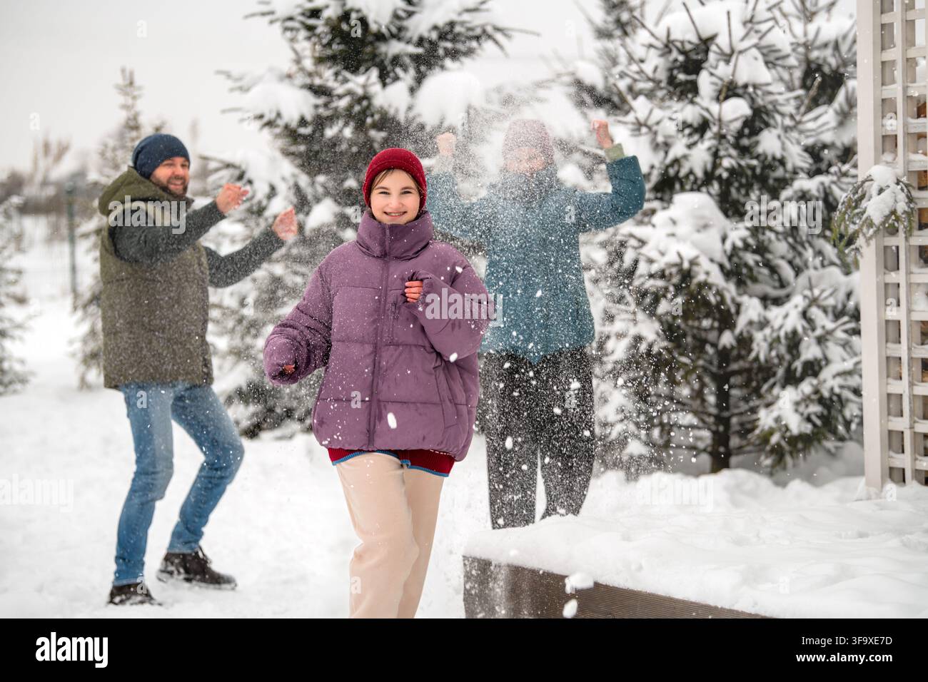 Famiglia felice che si diverte in una battaglia di palle di neve invernale Foto Stock
