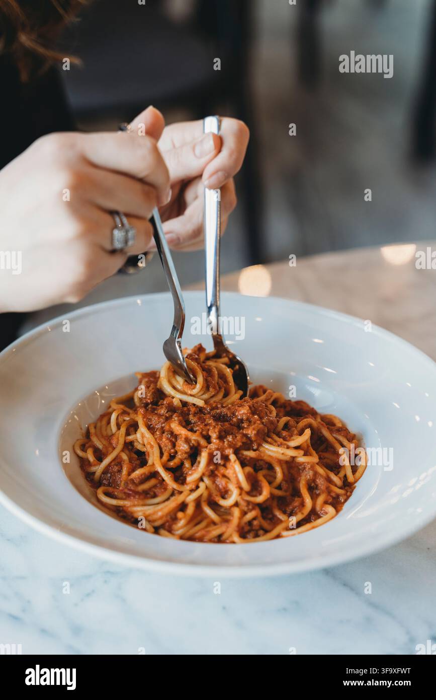 Donna che fa roteare deliziose spaghetti in una ciotola bianca Foto Stock
