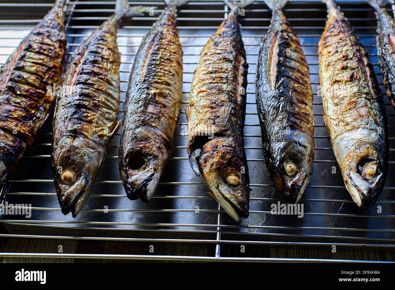 Pesce maccherello intero grigliato che si raffredda su una griglia metallica Foto Stock