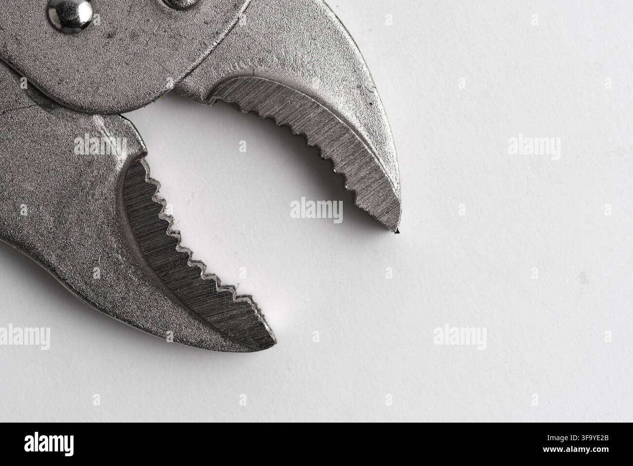 Primo piano estremo delle ganasce aperte di una pinza di bloccaggio metallica che mostra denti affilati e una superficie ruvida Foto Stock