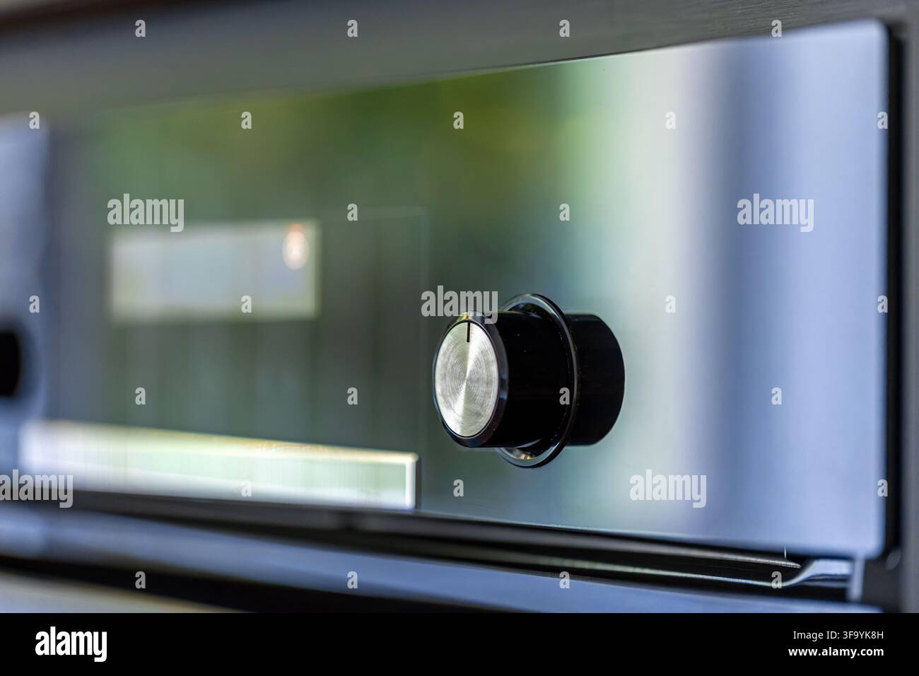 Manopola di controllo del forno su pannello riflettente. Dettaglio dell'interfaccia di un elettrodomestico da cucina in primo piano. Foto Stock