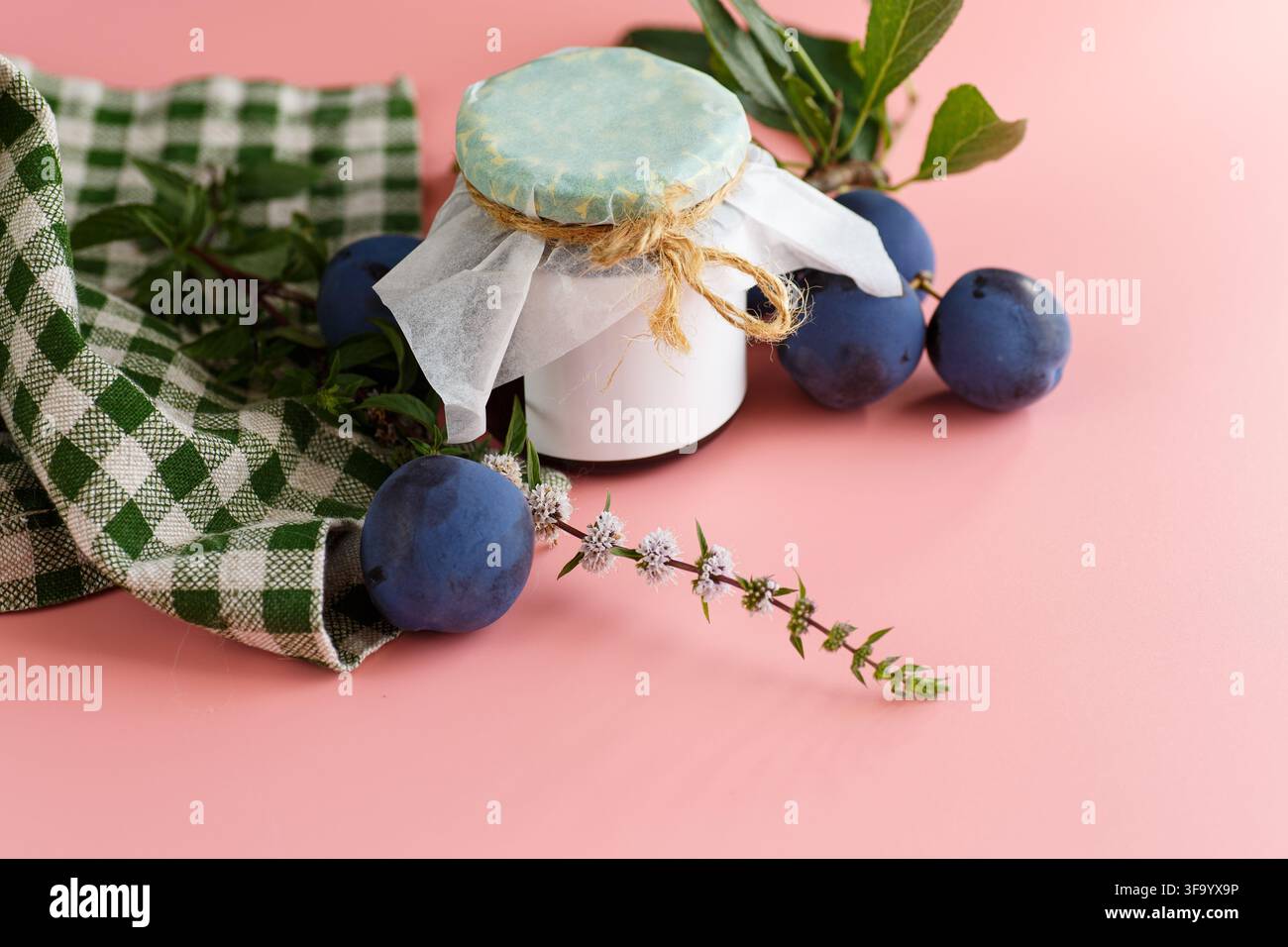 Marmellata di prugne fatta in casa con prugne fresche su sfondo rosa . Foto Stock