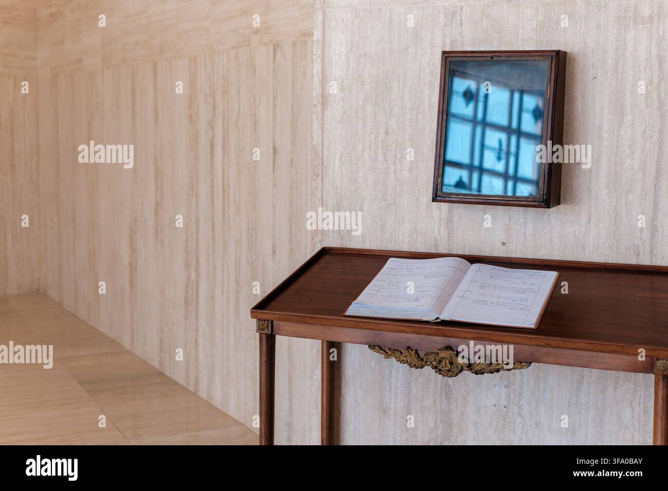 Vista di un libro degli ospiti su un tavolo di legno all'interno del cimitero italiano del Memoriale di Guerra di Al Alamein, con una vetrina e pareti in travertino ad Al Alamehel Foto Stock
