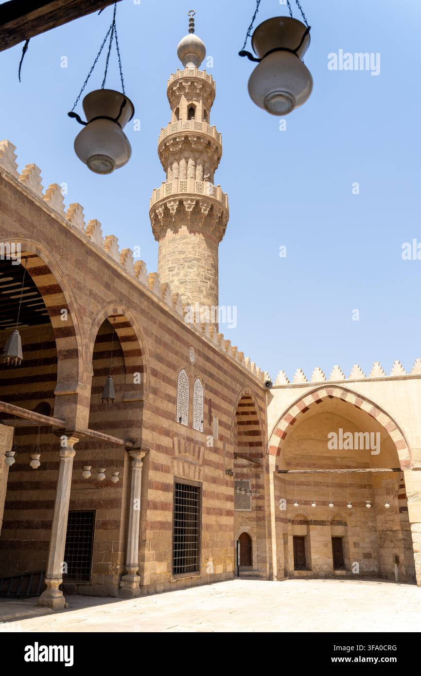 Vista della storica moschea di Aqsunqur con il suo minareto iconico e l'intricata muratura a strisce nel cortile sotto un cielo blu terso a El-Da Foto Stock