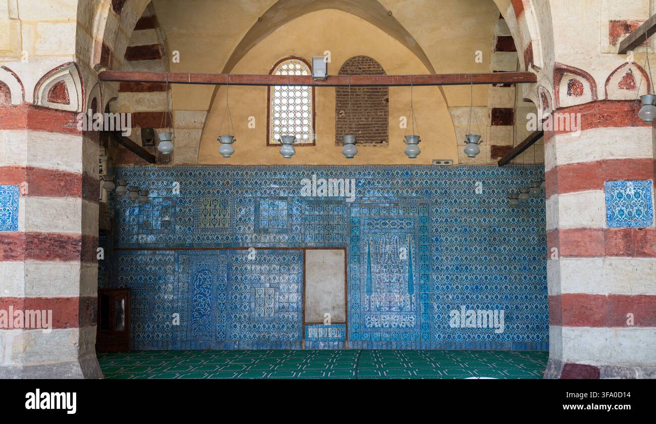 Vista delle intricate piastrelle blu di Iznik e delle colonne in pietra a strisce all'interno della storica moschea di Aqsunqur a El-Darb El-Ahmar, governatorato del Cairo, Egitto. Foto Stock
