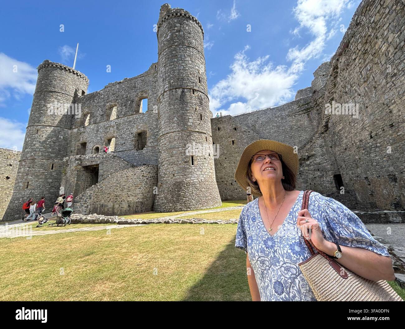 Un visitatore del castello di Harlech guarda in alto verso le mura della fortezza medievale. Foto Stock