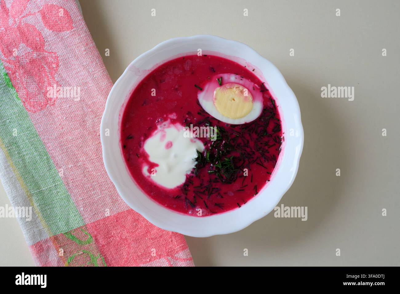 Zuppa fredda di barbabietola servita in una ciotola bianca con mezzo uovo sodo, panna acida e aneto. Concetto di cucina dell'Europa orientale, pranzo estivo rinfrescante Foto Stock