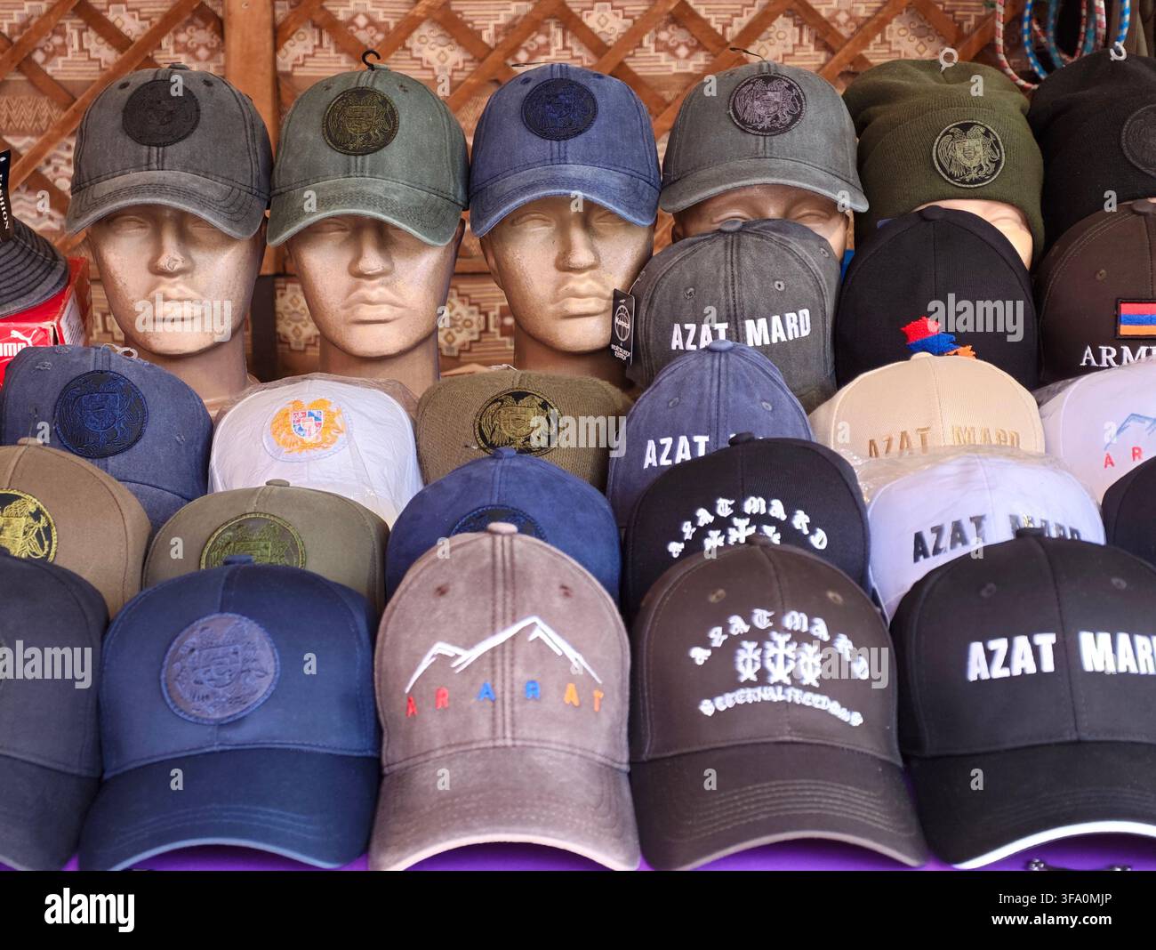 Manichini esibiscono vari cappelli con loghi e ricami. I colori vanno dal blu scuro al marrone e al grigio. I cappelli mostrano disegni tra cui montagne, testo, Foto Stock