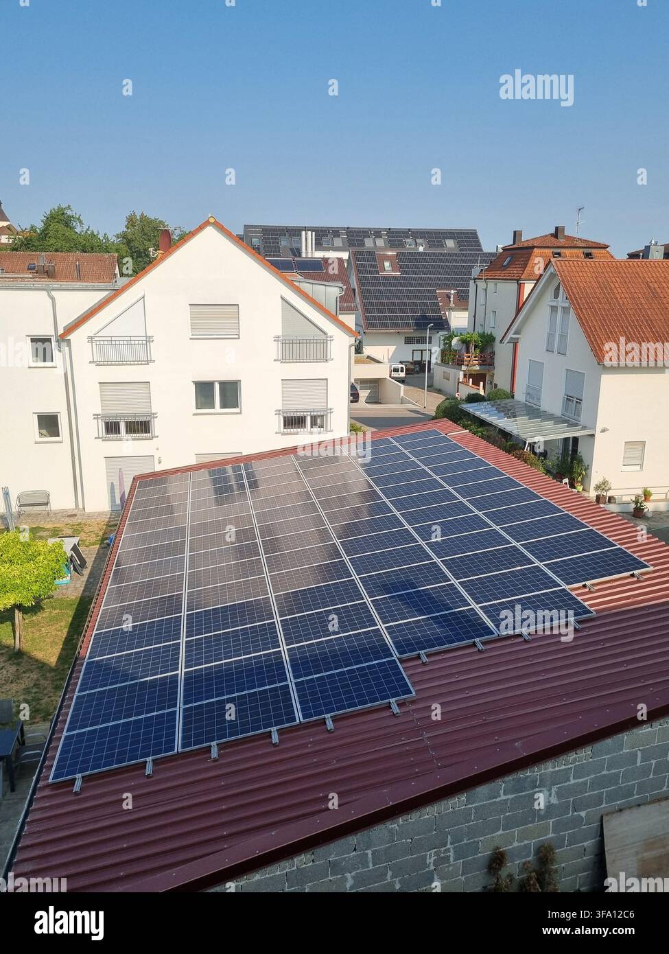 Vista elevata di un grande campo di pannelli solari installato su un tetto di tegole rosse in una città residenziale tedesca. Concetto di energia rinnovabile, energia solare, sustai - Immagine stock catturata con smartphone
