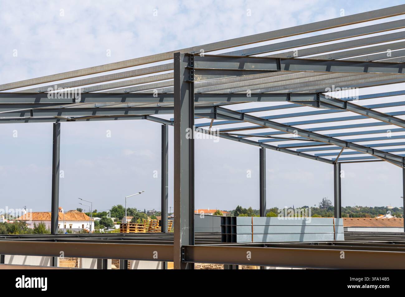 La struttura scheletrica di un grande edificio viene eretta con pesanti travi e colonne in acciaio sullo sfondo di nuvole sparse Foto Stock