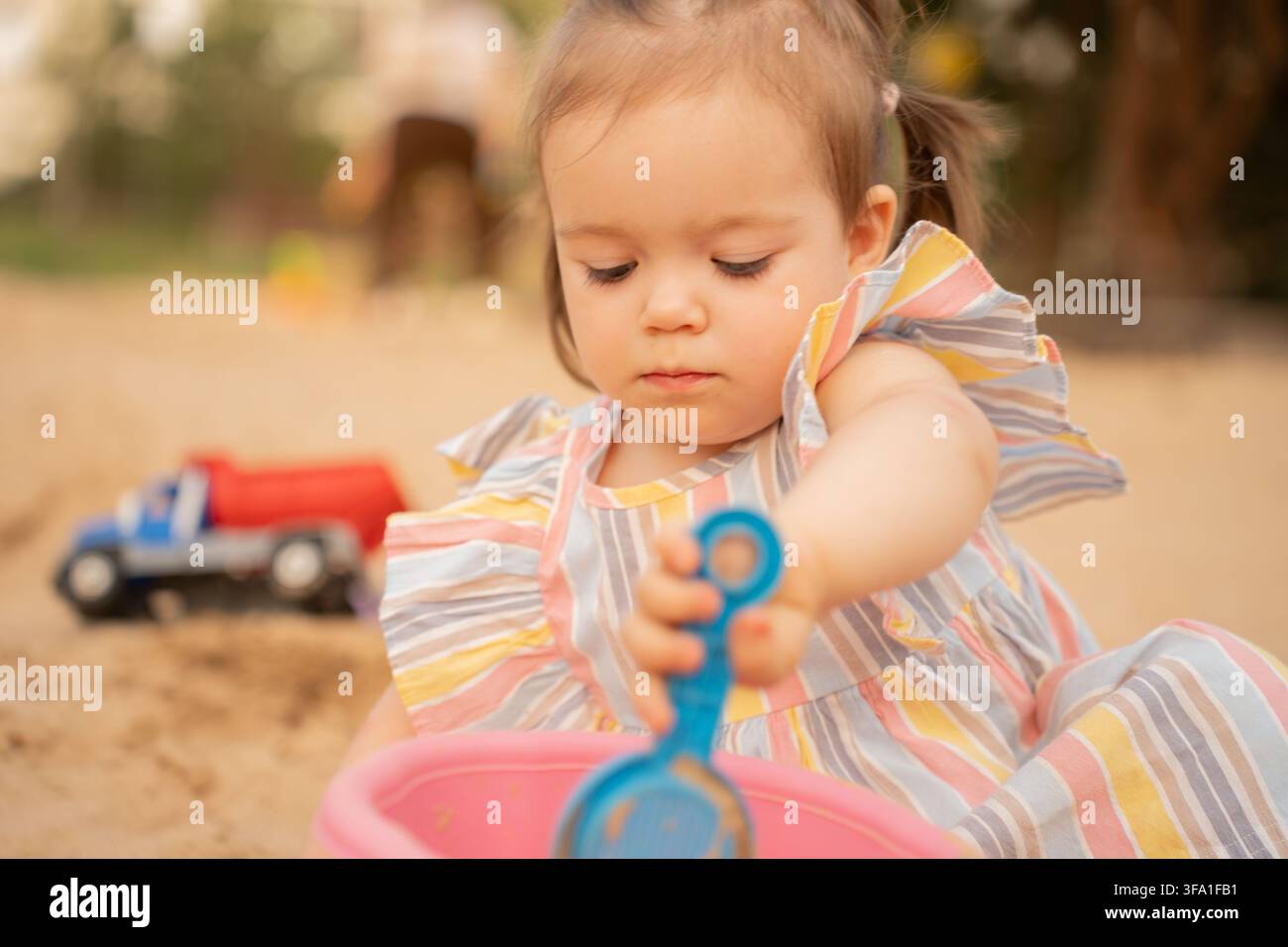 primissimo piano astratto di una figura umana sfocata accanto a un tessuto a strisce vivace e multicolore, che combina toni della pelle pesca, corallo, giallo, blu, bianco, g Foto Stock