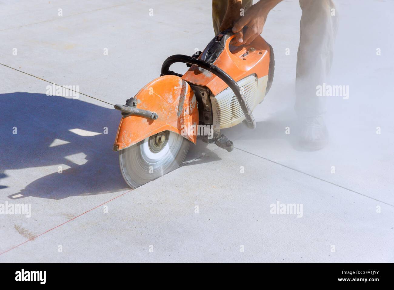 L'appaltatore aziona una sega per calcestruzzo in cantiere per effettuare tagli precisi sulla lastra. Foto Stock
