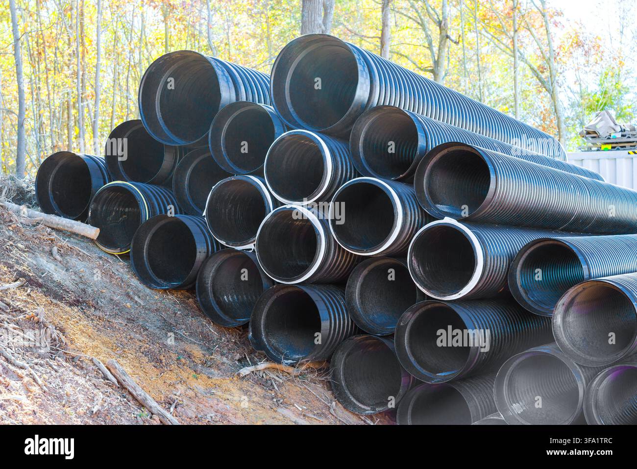 Diversi tubi di scarico neri sono disposti in pila nel cantiere edile Foto Stock