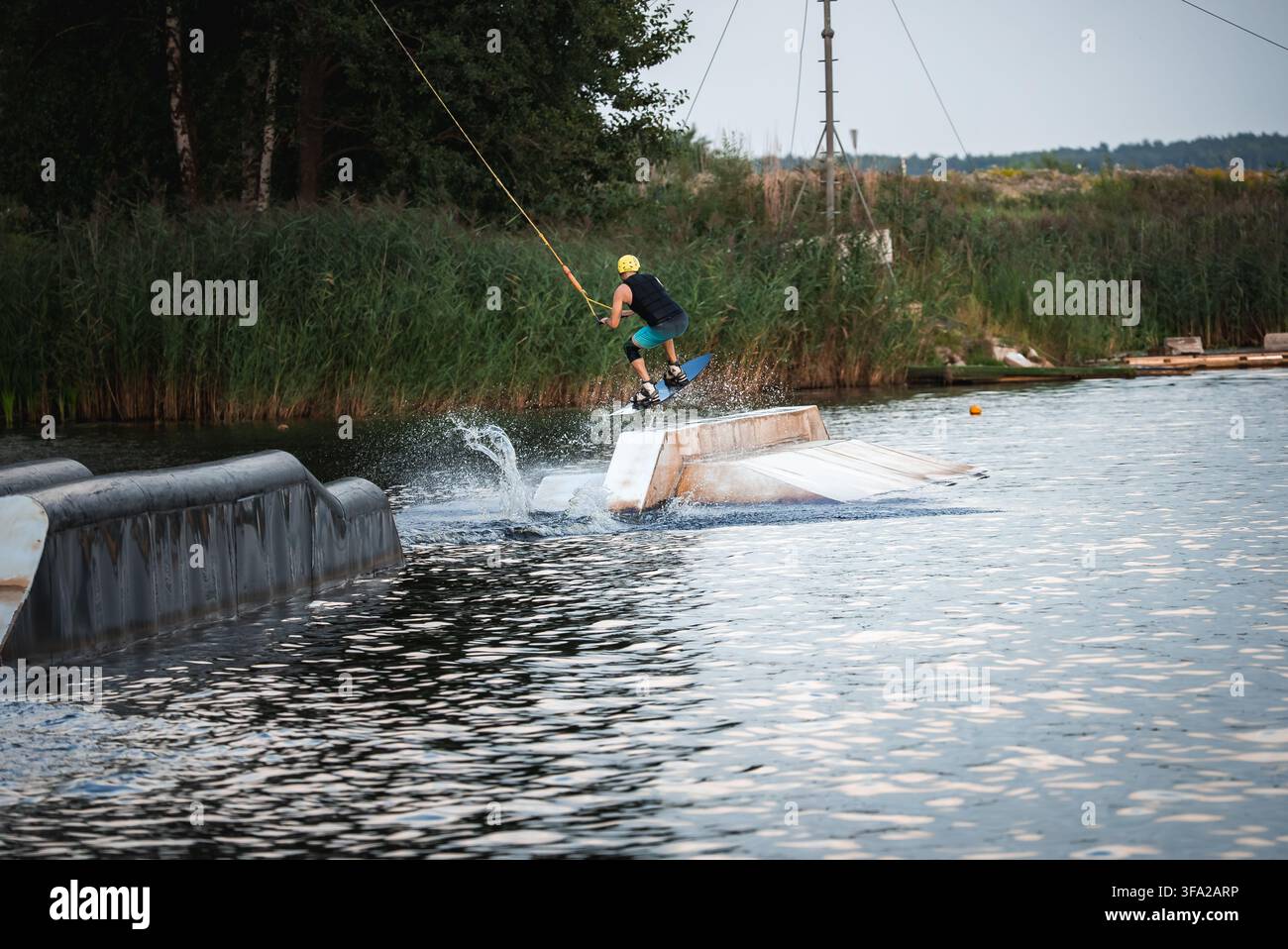 Il wakeboarder atterra da una rampa in una nuvola di schizzi. Foto Stock