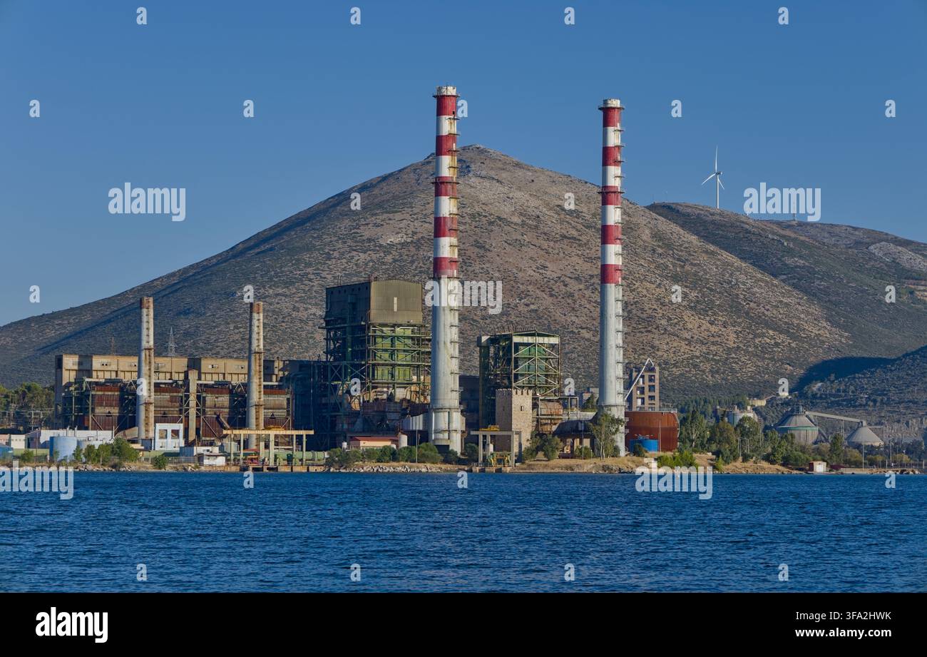 Ex centrale elettrica di Aliveri, torre medievale e turbina eolica distante ad Aliveri, Evia, Grecia. Foto Stock