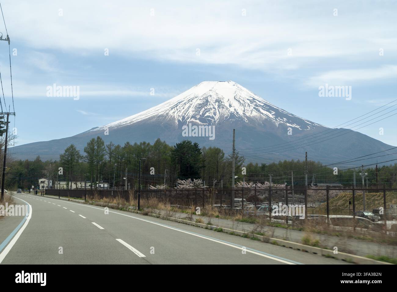 Il vulcano Monte Fuji coperto di neve tra l'area alberata e un'autostrada, Giappone Foto Stock