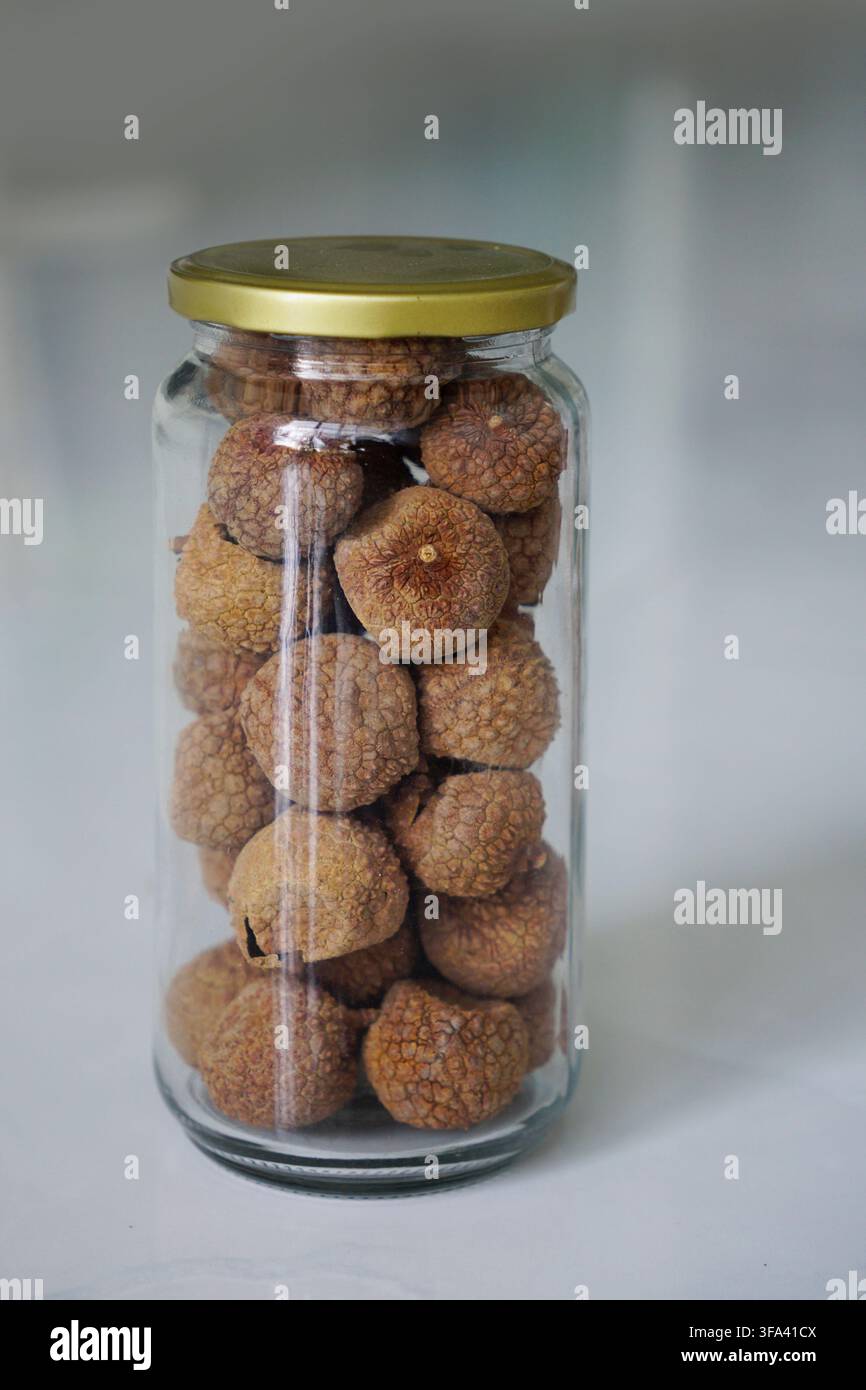 Litchi essiccati conservati in bottiglia di vetro con tappo d'oro in ottone Foto Stock