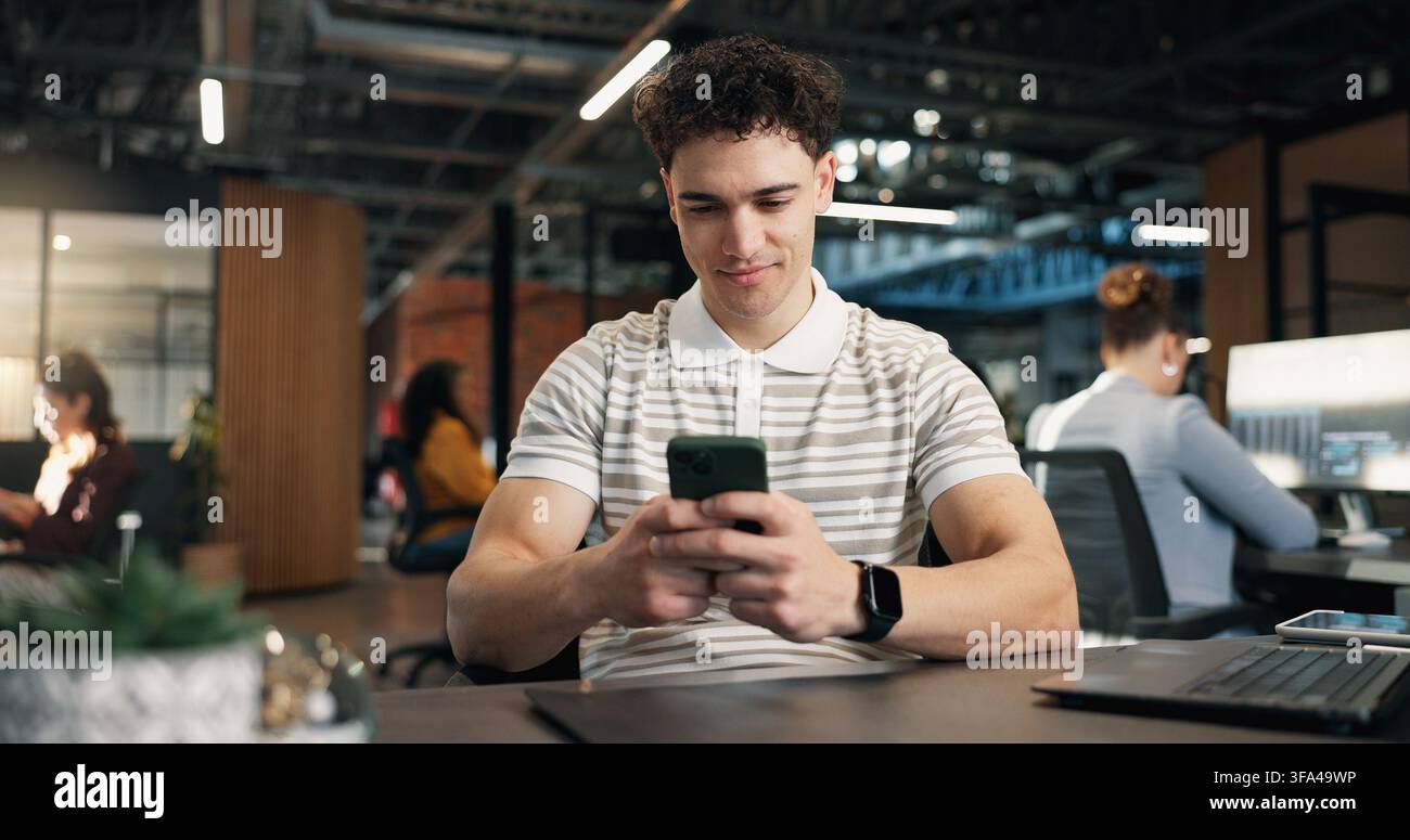 Uomo, che digita e legge in ufficio con telefono, sito web di ingegnere software o tendenze di ricerca per il progetto. App, coworking e persona in un'agenzia digitale con Foto Stock