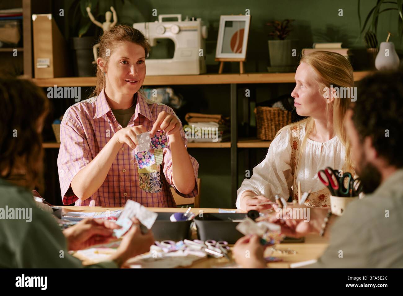 Donna creativa che insegna cucito e patchwork in un laboratorio artigianale Foto Stock
