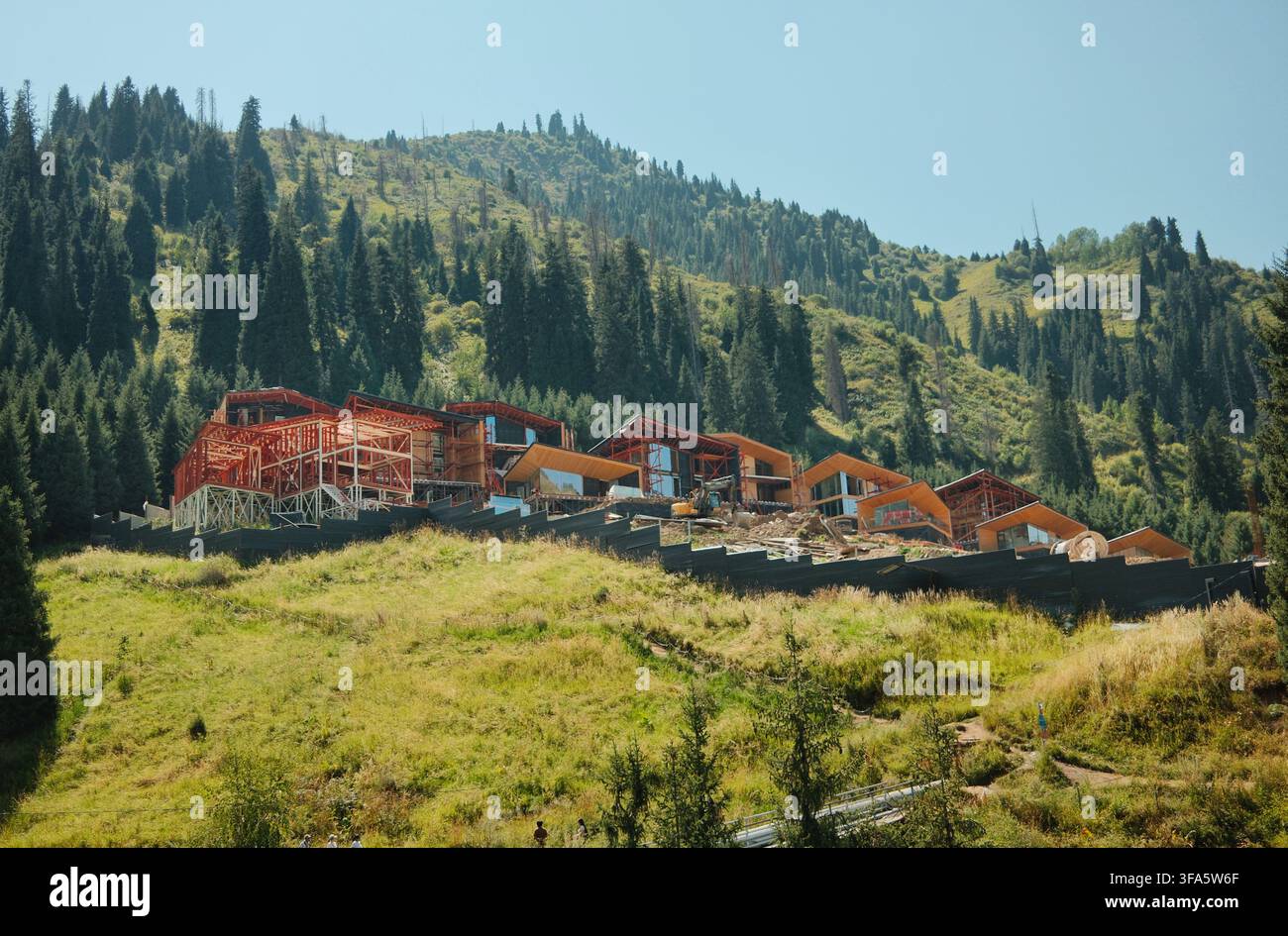 Un complesso di resort montano incastonato tra pendici rigogliose e foreste di conifere, che mostra una destinazione scenografica per il turismo, l'ospitalità e le attività all'aperto Foto Stock