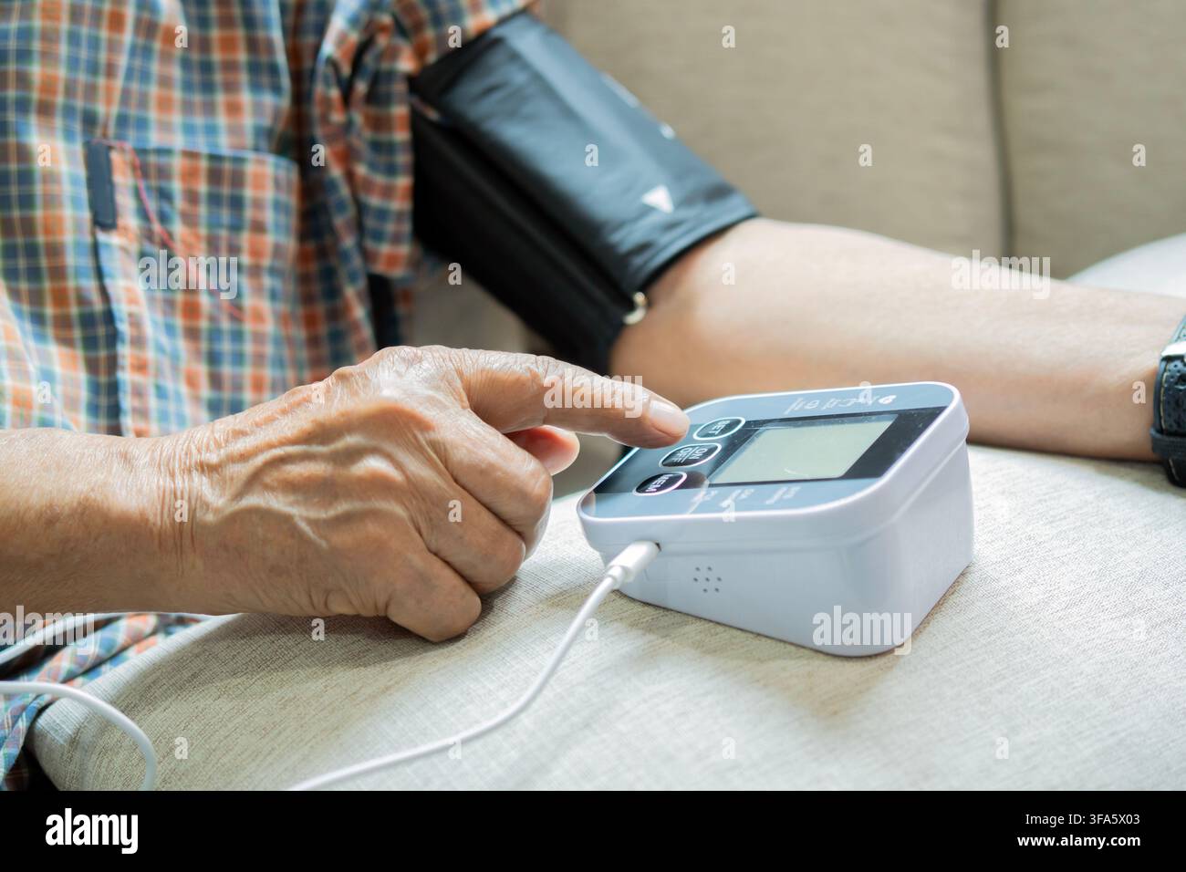 Mano di un anziano con automonitoraggio della pressione sanguigna a casa. Mostra autosufficienza, tecnologia sanitaria e gestione delle malattie croniche. Adatto per hea Foto Stock