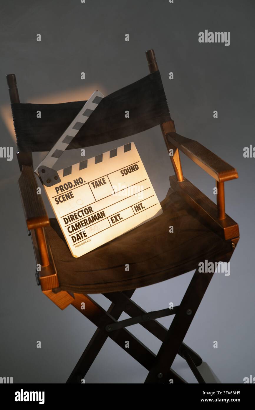 Sedia da regista con clapper sotto i riflettori in uno studio cinematografico. Foto Stock