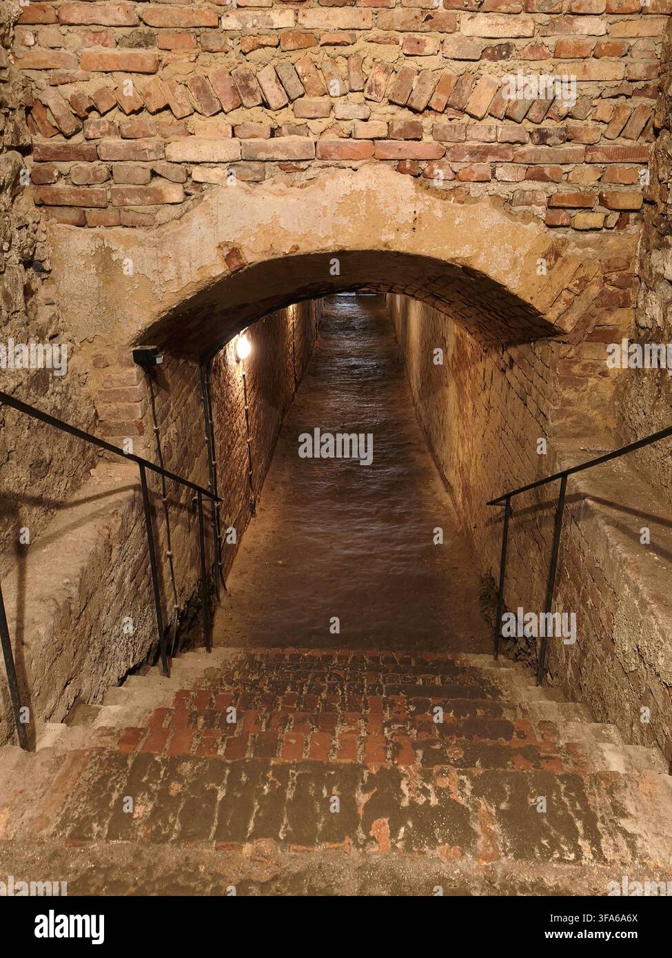 Una vecchia scala di mattoni che conduce in un stretto tunnel sotterraneo medievale. - Immagine stock catturata con smartphone