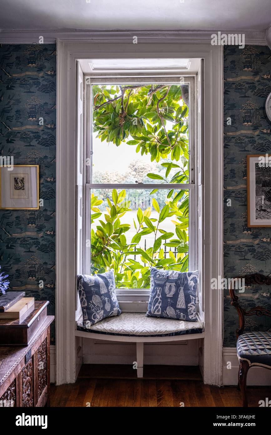 Posto vicino alla finestra con cuscini e vista sulle foglie del Tamigi nella casa georgiana di Marthe Armitage. Chiswick, Ovest di Londra, Regno Unito. Foto Stock