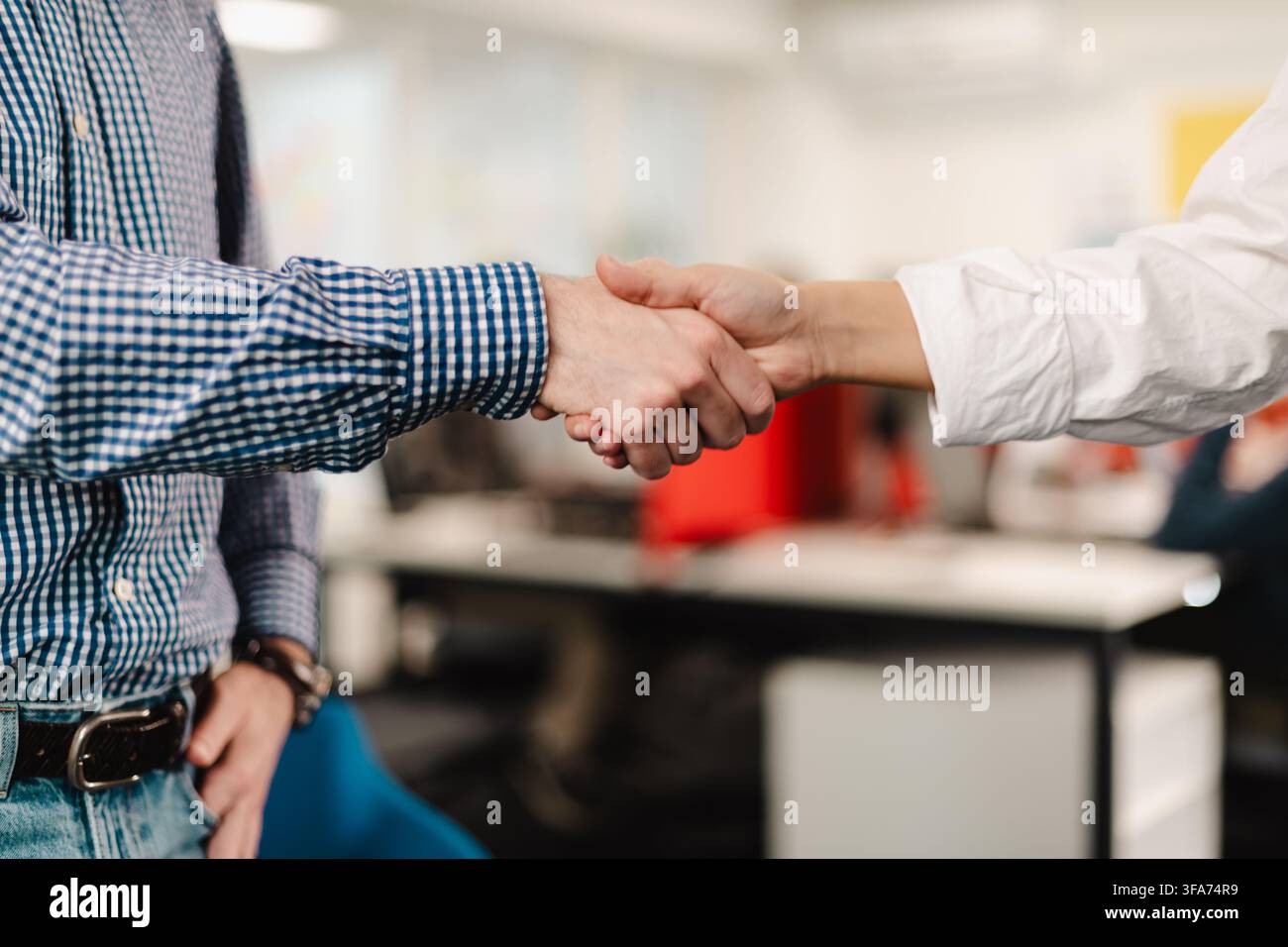 Incontro di lavoro tra due professionisti che si stringono la mano in un ambiente d'ufficio moderno durante il pomeriggio Foto Stock