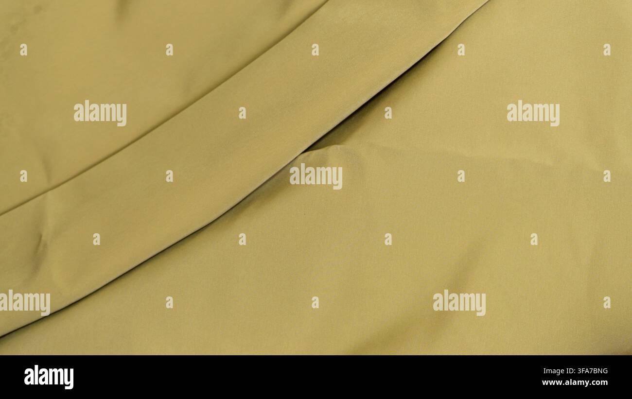 Sfondo in tessuto minimalista verde oliva con una singola piega diagonale prominente che attraversa la superficie liscia del tessuto. Il materiale drappeggiato con eleganza Foto Stock