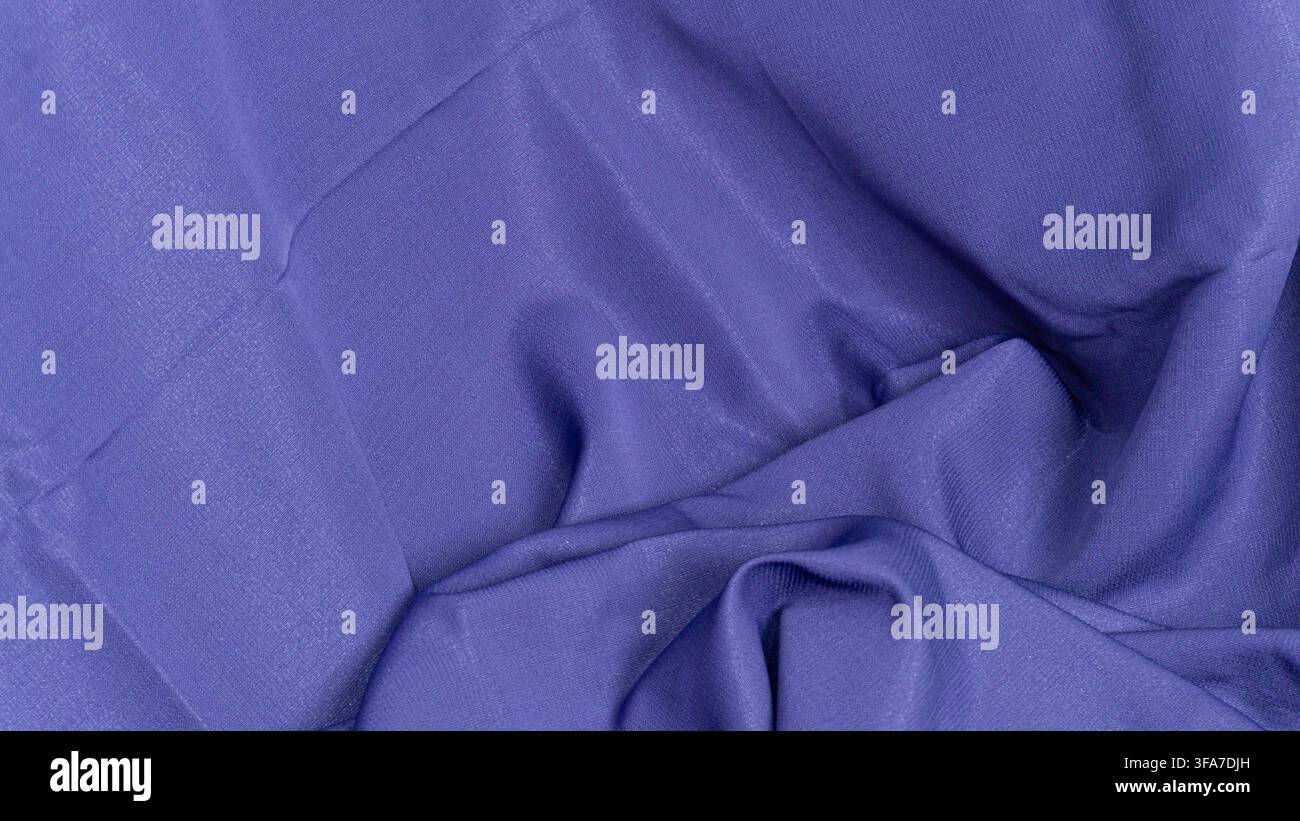 visivo presenta una magnifica prospettiva dall'alto di un morbido tessuto blu viola con onde drammatiche e pieghe eleganti raccolte sul lato destro. Foto Stock