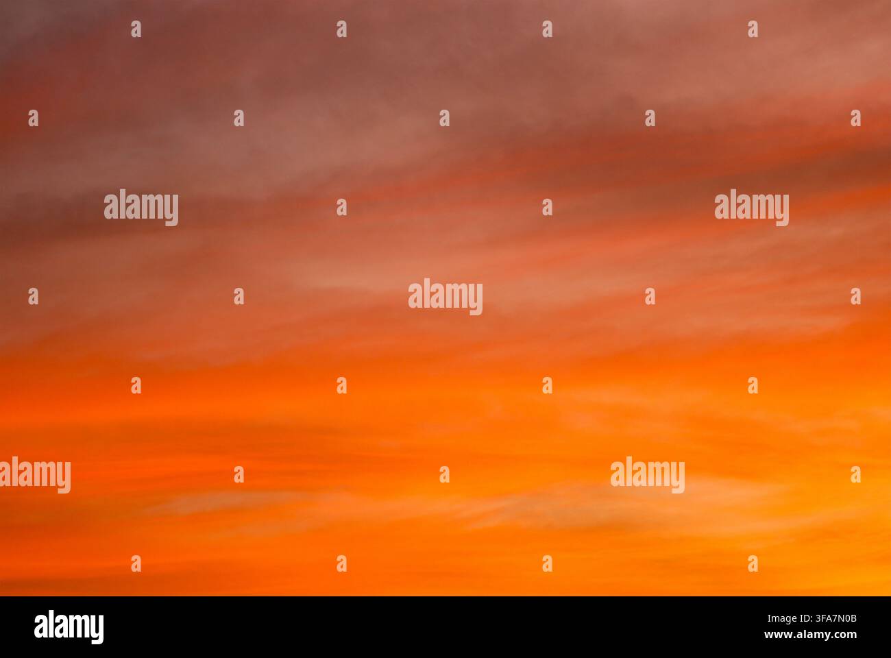 Cielo mozzafiato al tramonto o all'alba pieno di drammatiche nuvole arancioni e rosse infuocate, che creano una texture di sfondo naturale colorata. Foto Stock