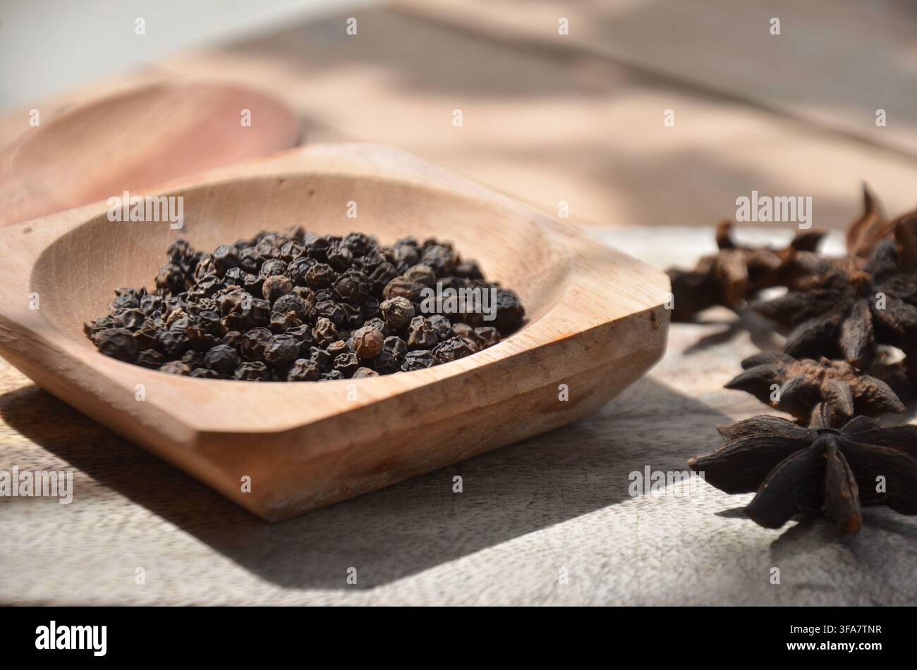 Spezia di anice stellato su superficie in legno rustico luce naturale calda sfondo di cibo aromatico. Foto Stock