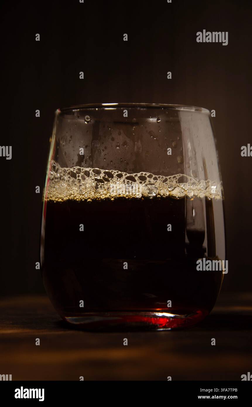 Versare caffè in un bicchiere su un tavolo di legno rustico scuro Foto Stock