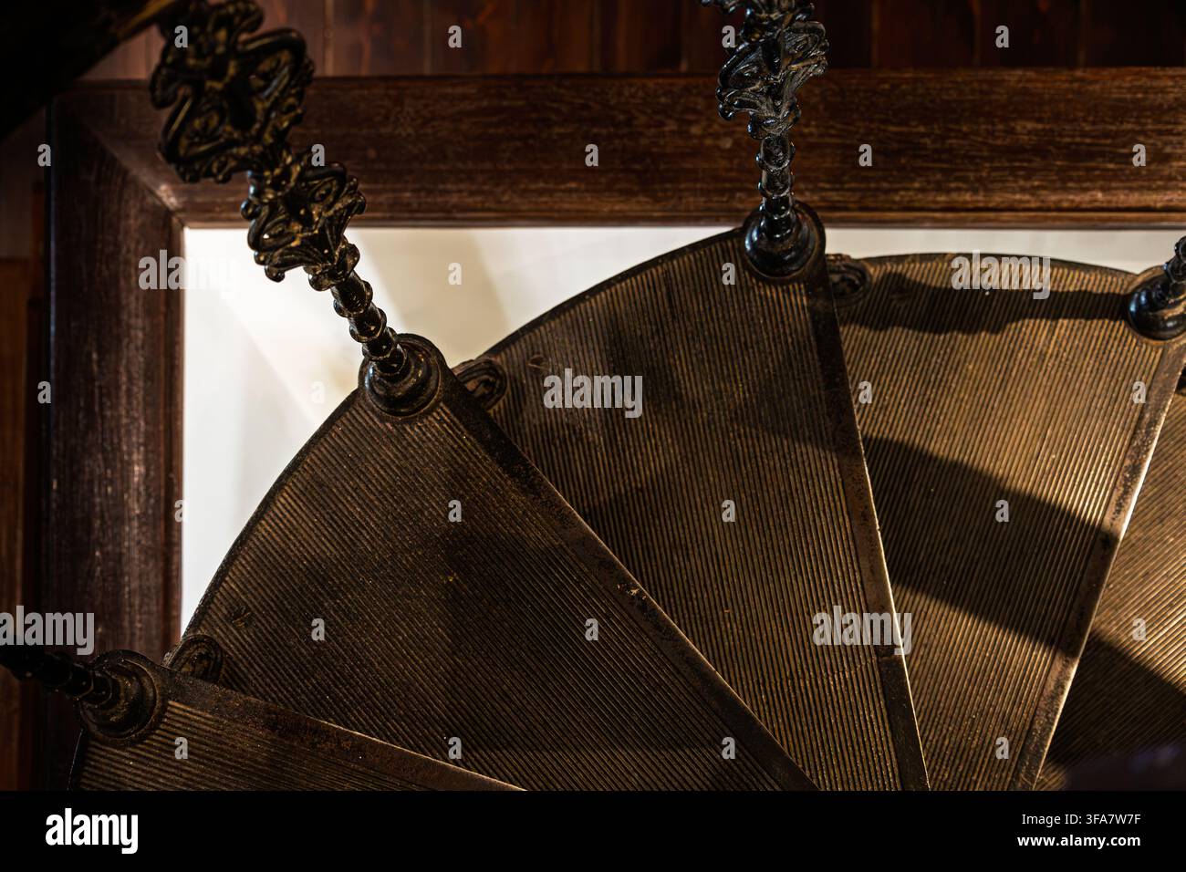Una vista ravvicinata di una storica scala a chiocciola in legno mostra gradini scanalati e una colonna centrale ornata con dettagli decorativi. Foto Stock