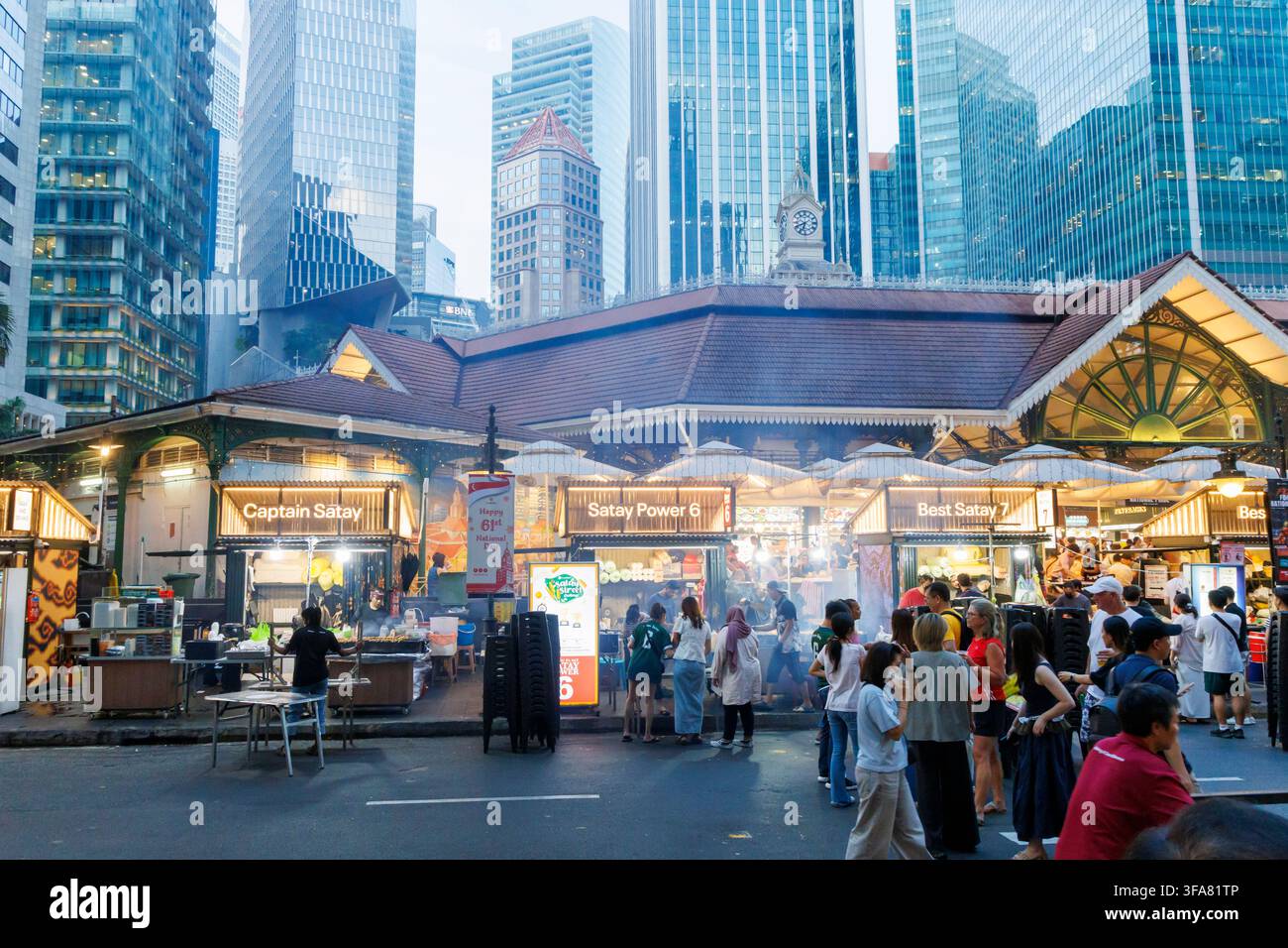 Lau Pa Sat, un centro alimentare o food court a Singapore, ospitato in un edificio vittoriano in ghisa, situato contro lo sfondo di grattacieli moderni Foto Stock
