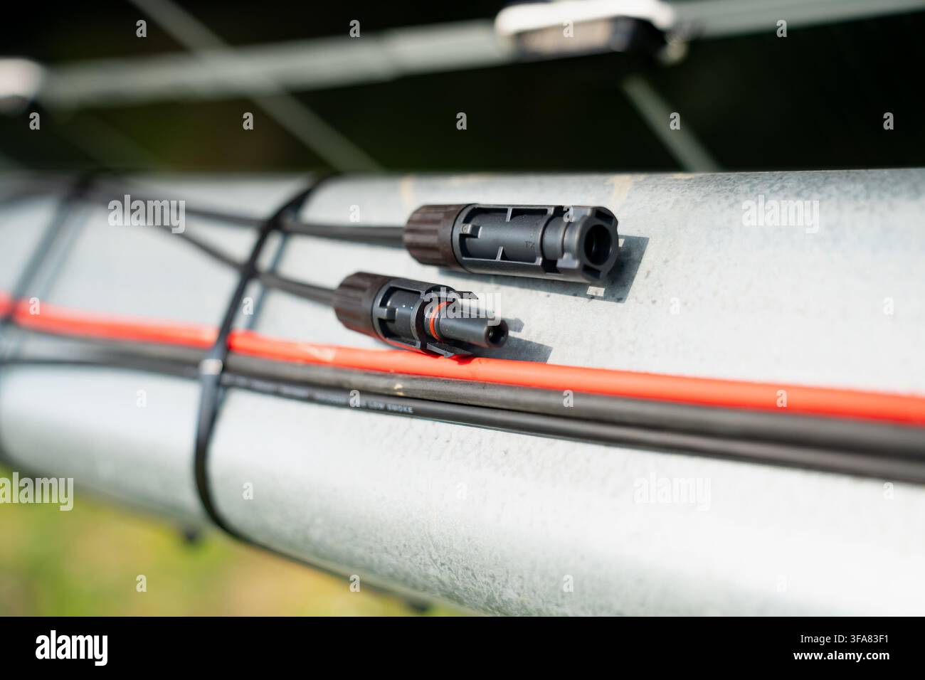 Primo piano di connettori solari MC4 maschio e femmina appoggiati su una struttura di montaggio metallica durante l'installazione di un sistema di energia rinnovabile Foto Stock