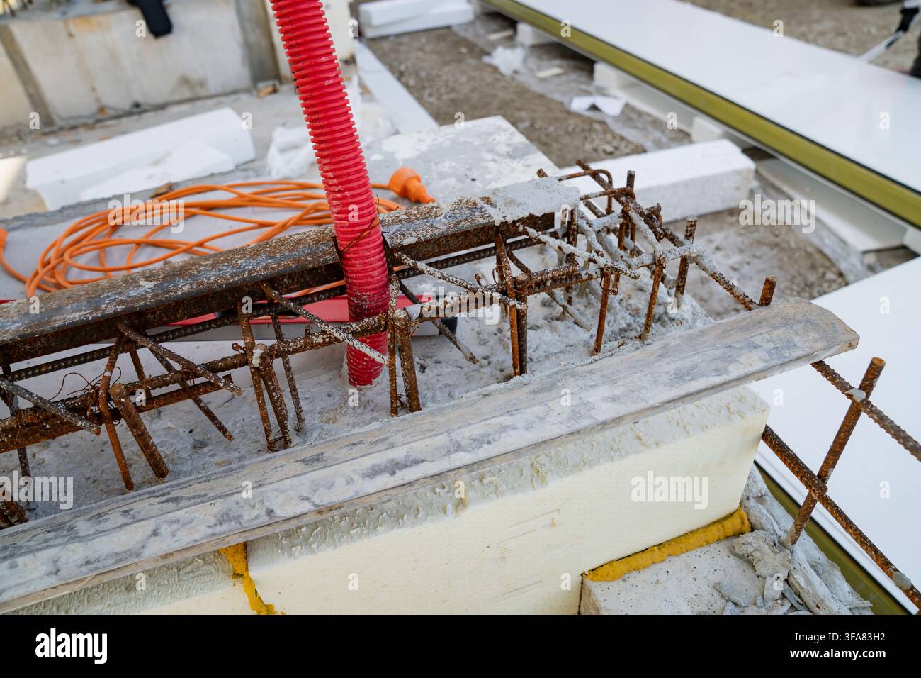 Cesta di rinforzo in acciaio inserita in una lastra di fondazione in cemento con installazione di un tubo elettrico corrugato in plastica Foto Stock
