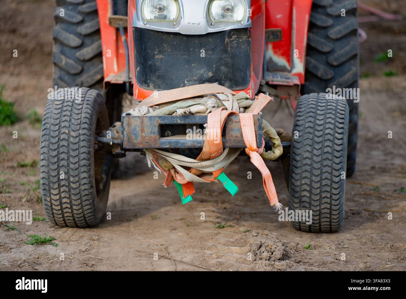 Ruote anteriori e meccanismo dell'asse sterzante di un trattore agricolo compatto dotato di cinghie di recupero per lavori agricoli utilitari Foto Stock