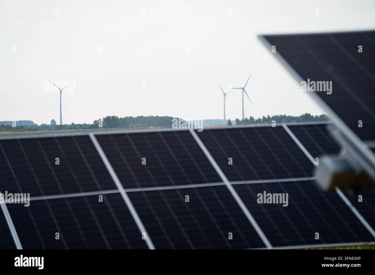 Installazione ibrida di energia rinnovabile con array di pannelli fotovoltaici e turbine eoliche che rappresentano la transizione energetica verde Foto Stock