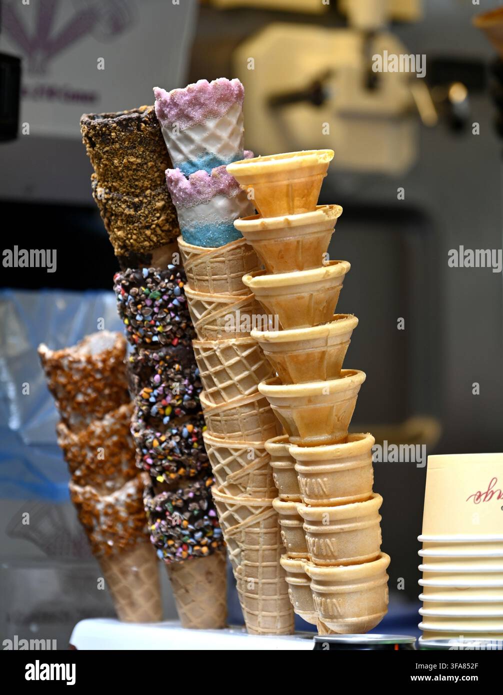 Pile di coni gelato vuoti, alcuni con rivestimento al cioccolato o alle noci Foto Stock