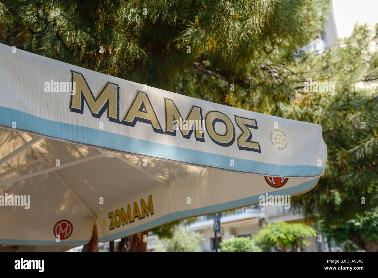 Ombrello con testo greco che pubblicizza un marchio di birra in un ambiente urbano, Patrasso, Grecia. Foto Stock