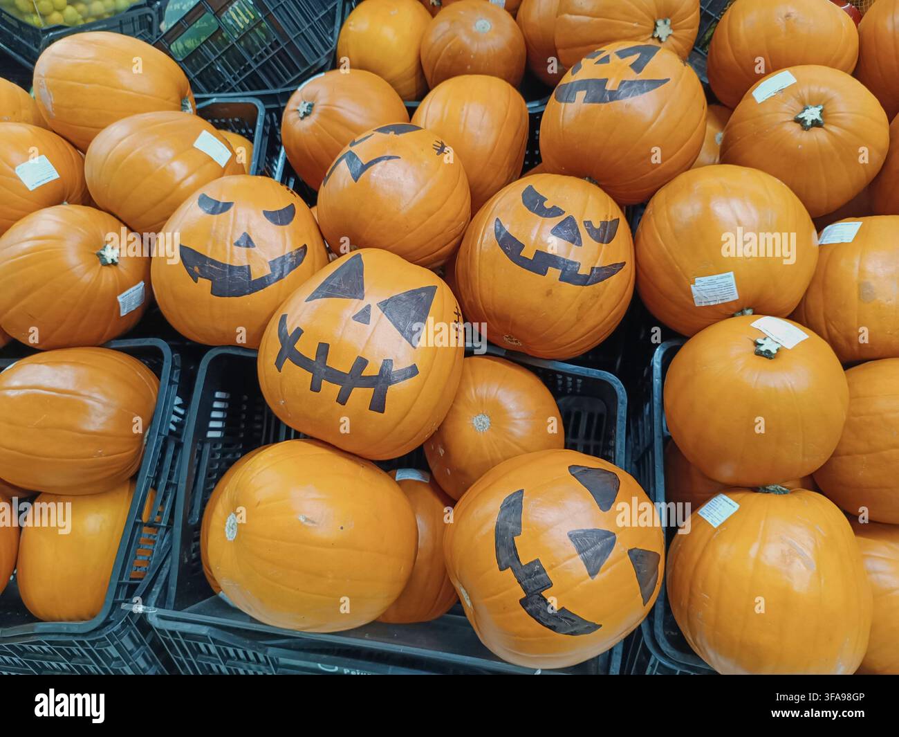 Zucche Jack-o'-lantern che mostrano facce spaventose in un cesto del negozio Foto Stock