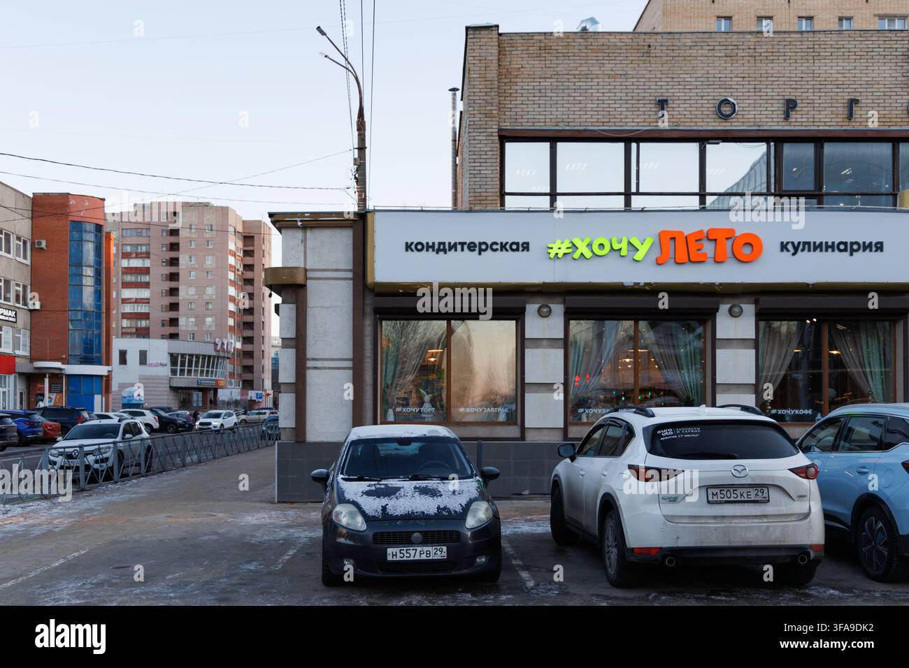 Un edificio di una pasticceria locale nella città settentrionale in una fredda giornata invernale con un cartello luminoso e allegro che si traduce come Voglio l'estate. Foto Stock
