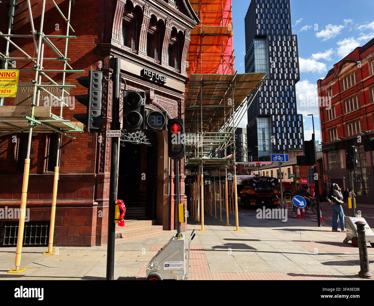 Manchester, UK - 10 maggio 2026: Pub storico Refuge sotto impalcatura accanto a una torre moderna a Manchester, UK con semafori e pedoni. Foto Stock