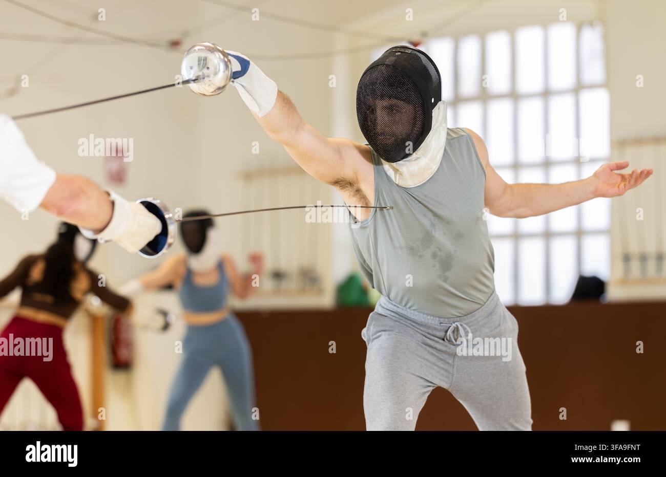 Un gruppo di recinti si allena in duelli e fa uscire i colpi sui cuscini in palestra Foto Stock