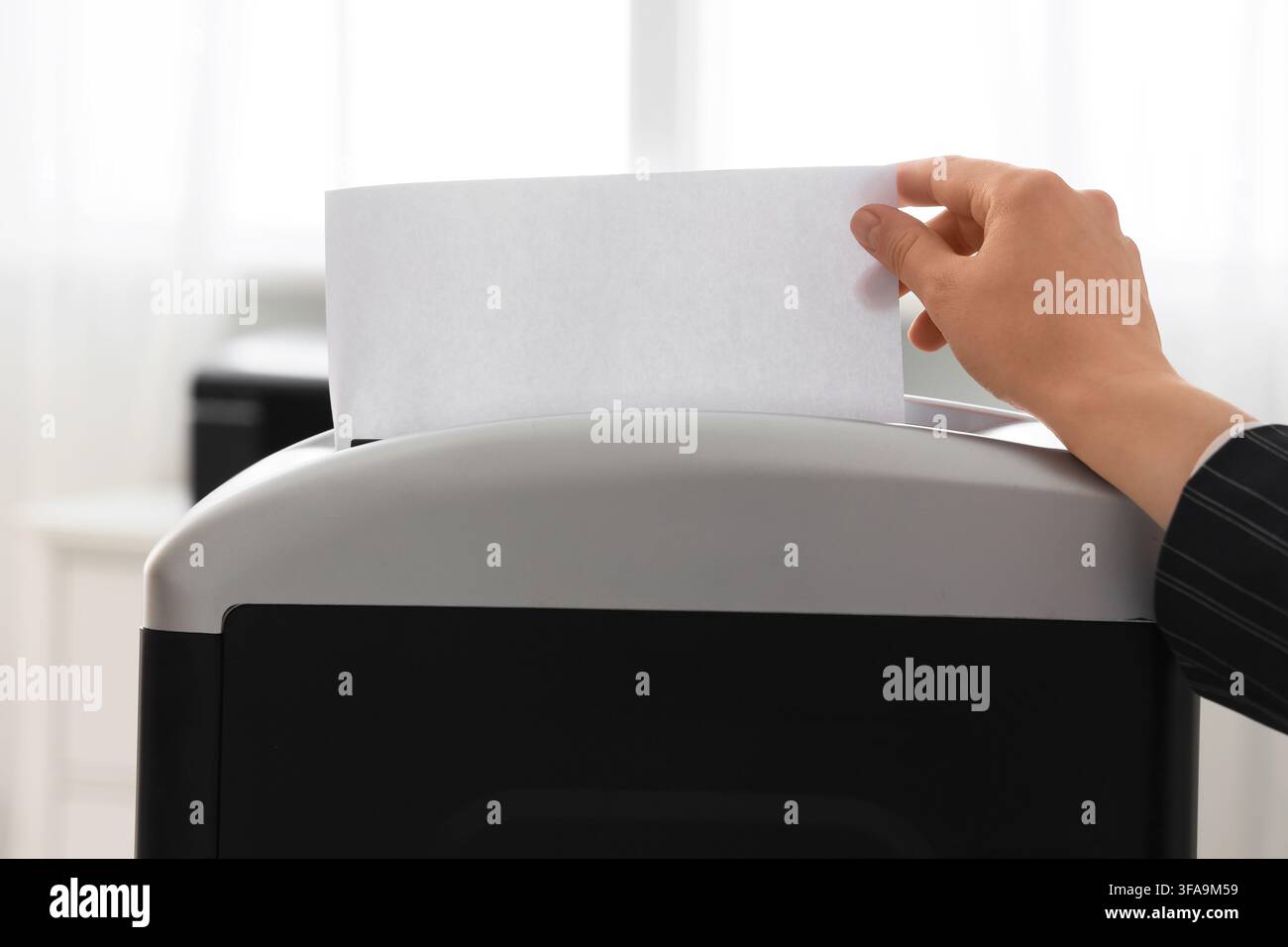 Sicurezza dei dati e protezione della privacy, una persona distrugge documenti riservati in un ambiente d'ufficio Foto Stock