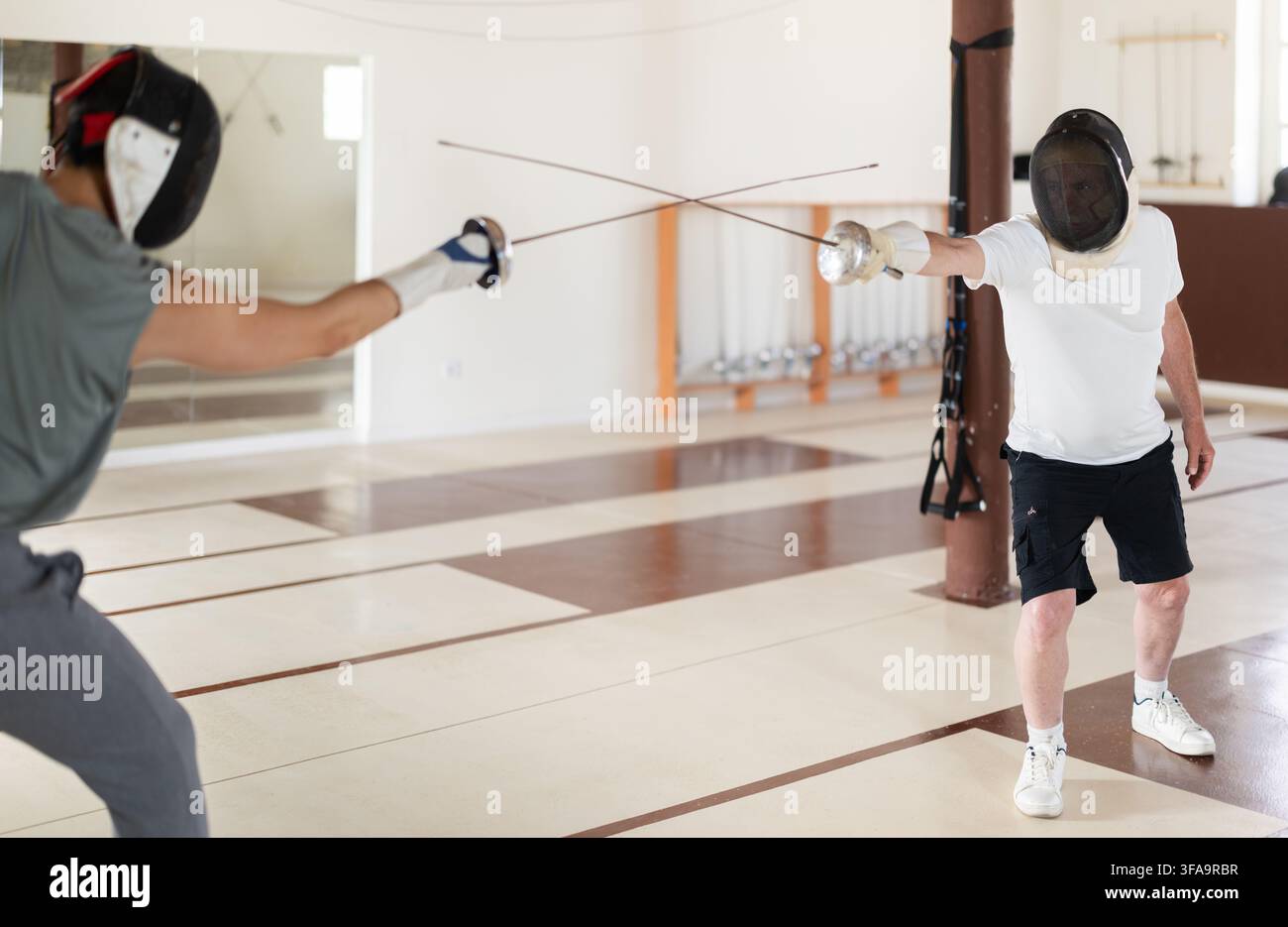 Un gruppo di recinti si allena in duelli e fa uscire i colpi sui cuscini in palestra Foto Stock