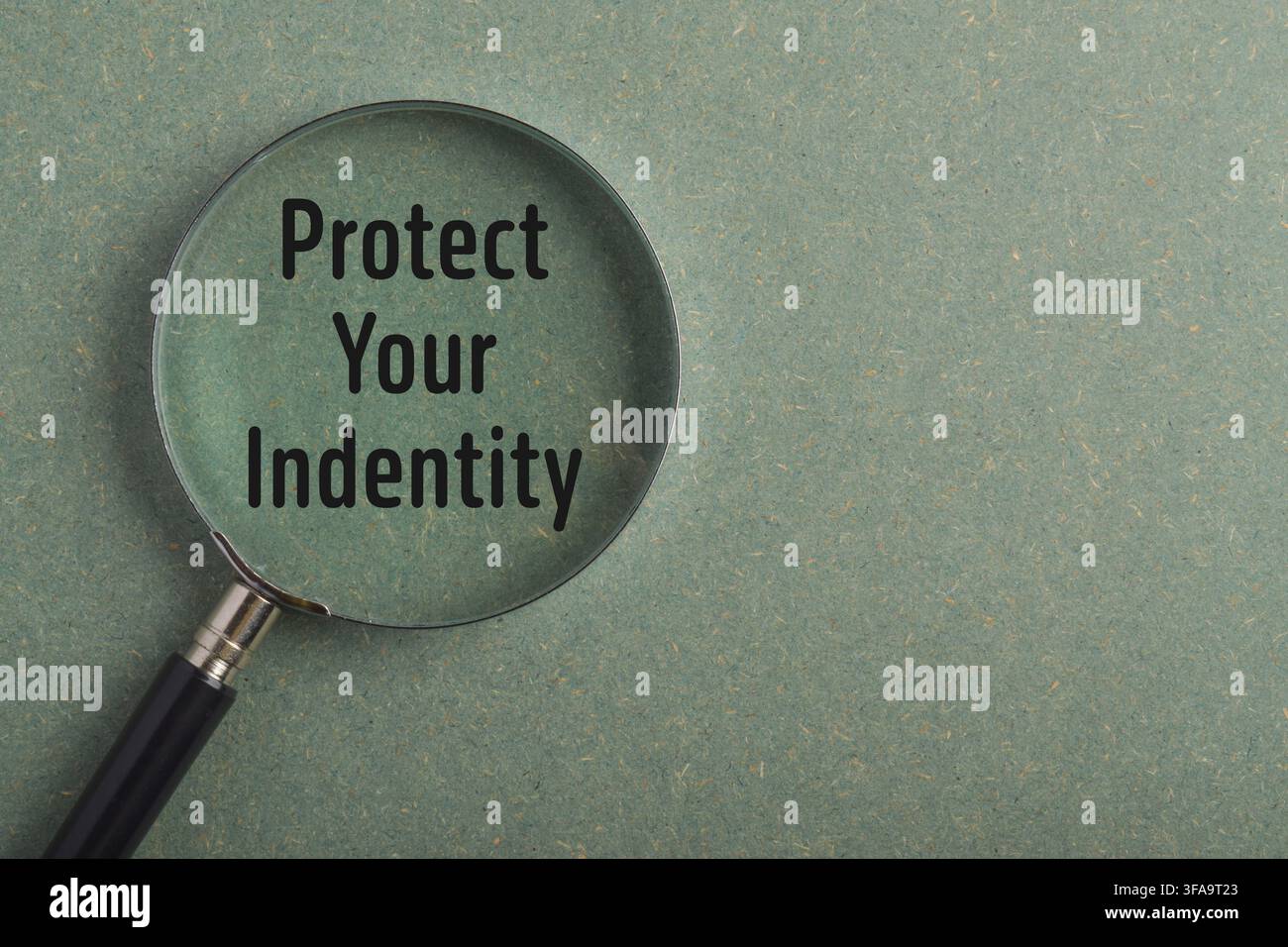 Messaggio di protezione della tua identità visualizzato attraverso una lente d'ingrandimento. Concetto per la prevenzione del furto d'identità, la sicurezza dei dati personali, la protezione della privacy Foto Stock